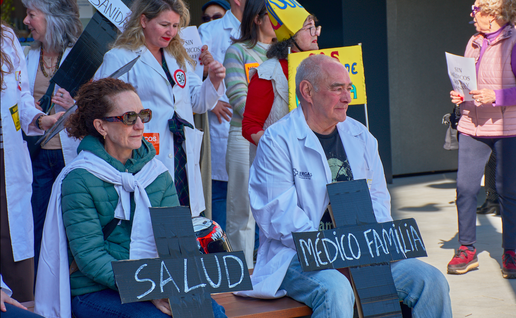 Doctors sitting down during a protest holding banners in shape of a cross
