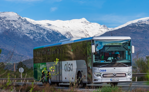 Alsa coach travelling along a motorway with Sierra Nevada in the background