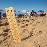 Thermometer showing high temperatures on a crowded beach in Spain during a summer heatwave.