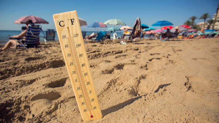 Thermometer showing high temperatures on a crowded beach in Spain during a summer heatwave.