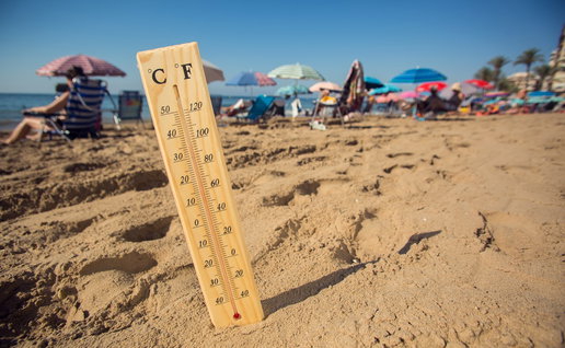 Thermometer showing high temperatures on a crowded beach in Spain during a summer heatwave.