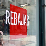 Shop window in Spain displaying a large “Rebajas” sign for summer sales.