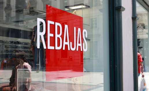 Shop window in Spain displaying a large “Rebajas” sign for summer sales.