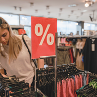 Woman searches through clothes store sales.