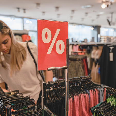 Woman searches through clothes store sales.
