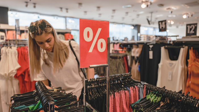 Woman searches through clothes store sales.