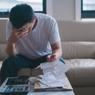 Worried man reviewing bills and financial documents at home amid debt concerns.