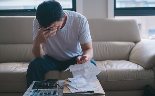 Worried man reviewing bills and financial documents at home amid debt concerns.