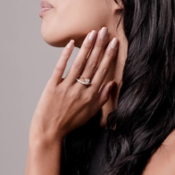 Female holding her hand up to her face showing a Diamond ring on her middle finger
