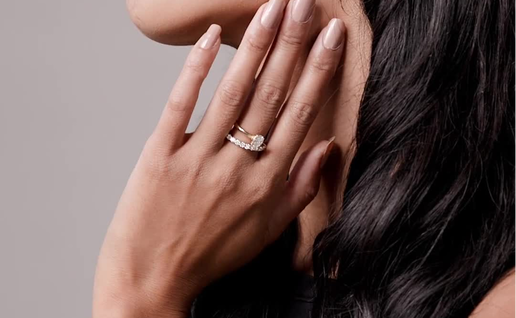 Female holding her hand up to her face showing a Diamond ring on her middle finger