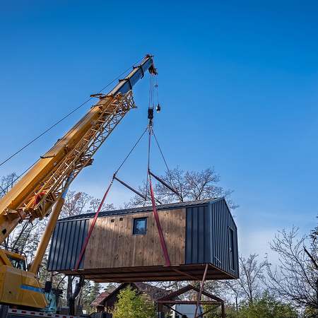Prefabricated house being lifted by crane.