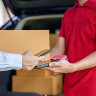 Male delivery person delivering package and customer paying with credit card