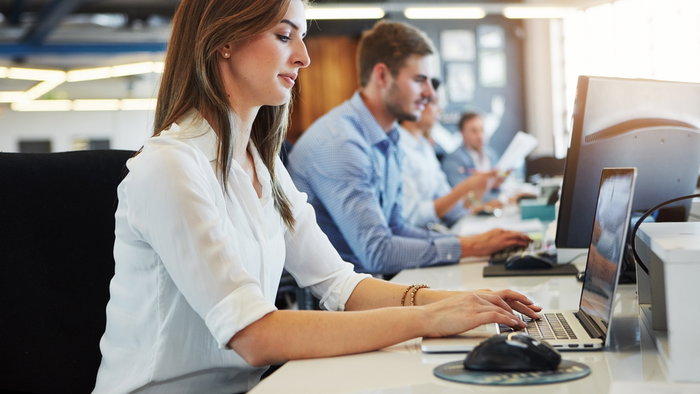 Business woman on laptop in a office taking customer enquiries