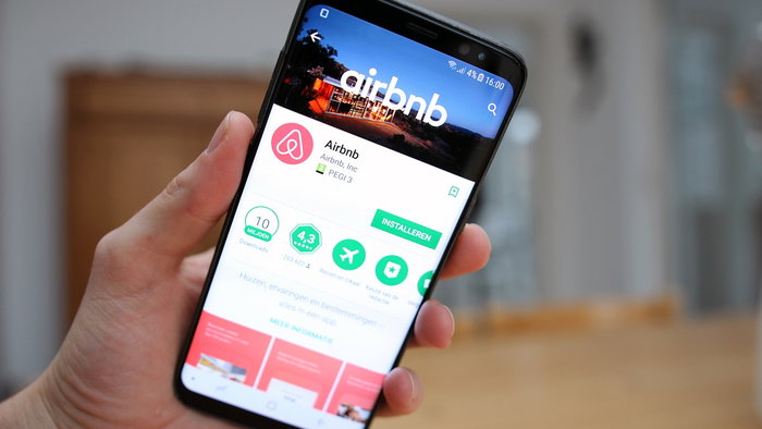 A person holds a smartphone displaying the Airbnb app, illustrating the growing role of short-term rental platforms in the holiday accommodation market.
