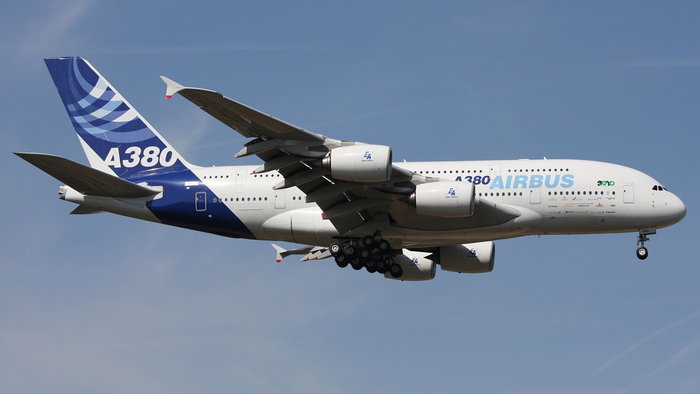 An Airbus A380 passenger aircraft in flight with its landing gear down during approach.