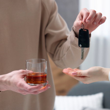 Driver hands over car keys after drinking alcohol, highlighting the importance of responsible driving.