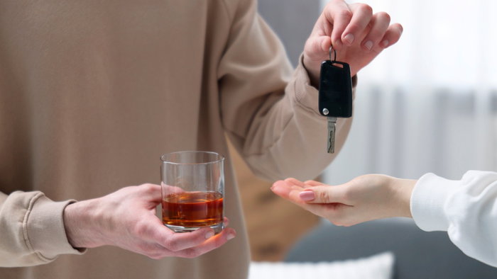 Driver hands over car keys after drinking alcohol, highlighting the importance of responsible driving.
