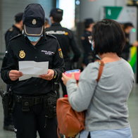 Spanish National Police officers carry out document checks on a traveller at an airport border control point in Spain.