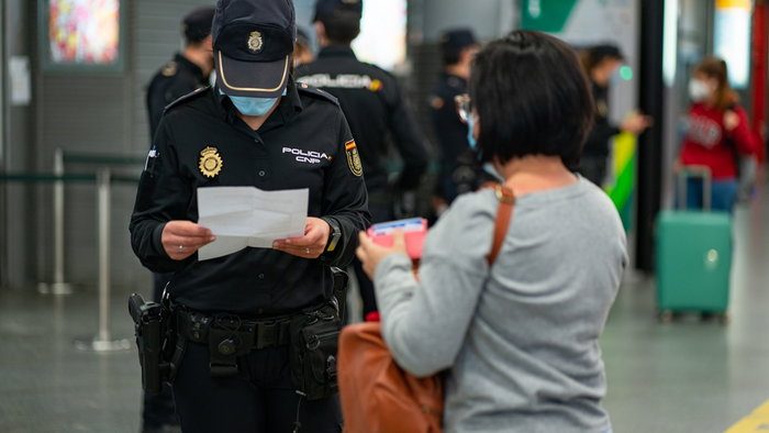 Spanish National Police officers carry out document checks on a traveller at an airport border control point in Spain.