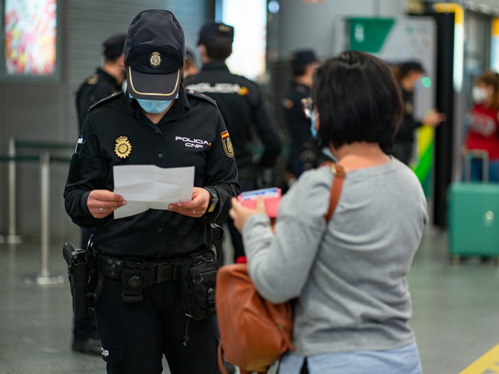 Spanish National Police officers carry out document checks on a traveller at an airport border control point in Spain.