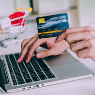 Person making an online purchase with a credit card while shopping on a laptop.