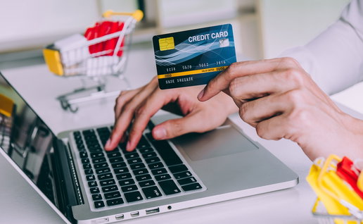 Person making an online purchase with a credit card while shopping on a laptop.