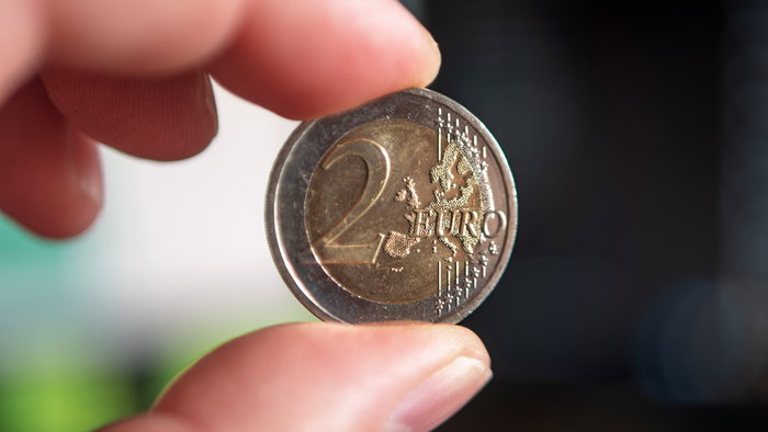 A €2 euro coin held between two fingers, illustrating the rare Monaco commemorative coin that has become highly sought after by collectors.