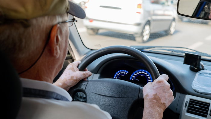 An older driver behind the wheel of a car, illustrating Spain's licence renewal and medical assessment rules for motorists over 65.