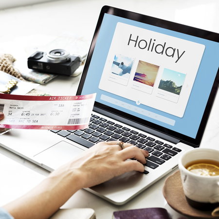 Traveller booking a holiday online using a laptop, with travel tickets and holiday accommodation options displayed on screen.