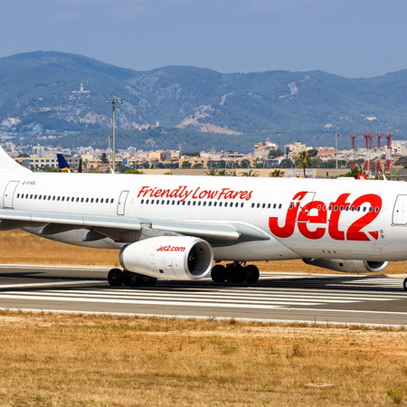 A Jet2 aircraft on the runway at Palma de Mallorca Airport with the Tramuntana mountains in the background.
