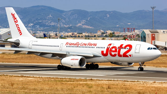 A Jet2 aircraft on the runway at Palma de Mallorca Airport with the Tramuntana mountains in the background.