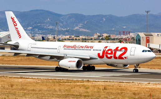A Jet2 aircraft on the runway at Palma de Mallorca Airport with the Tramuntana mountains in the background.