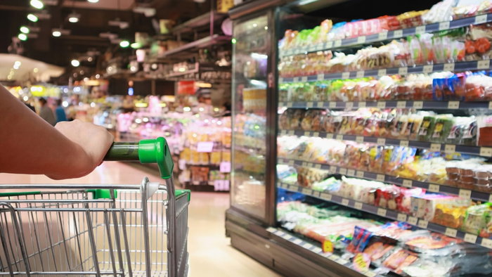 woman hand hold supermarket shopping cart with Abstract grocery store