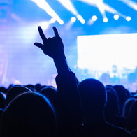 Fans at live rock music concert cheering musicians on stage, back view