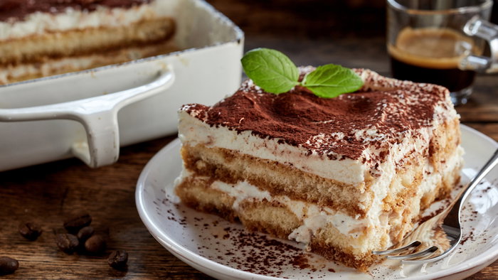 Close up on a portion of gourmet tiramisu Italian dessert topped with a sprig of mint served on a plate at table in a side view