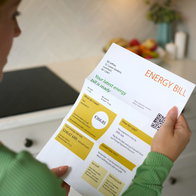 A woman looking at an energy bill receipt