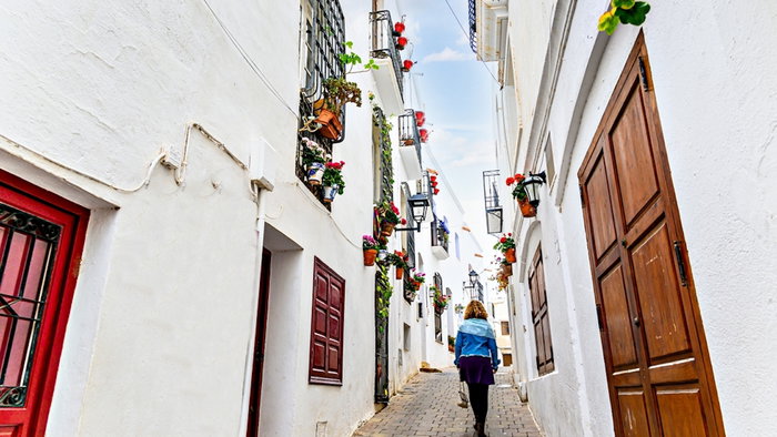 Blonde woman with curly hair walking through the streets of the picturesque town in Spain