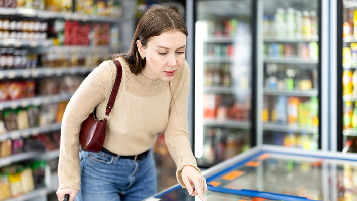Woman checking chocolate coated ice creams in a supermarket freezer in Spain