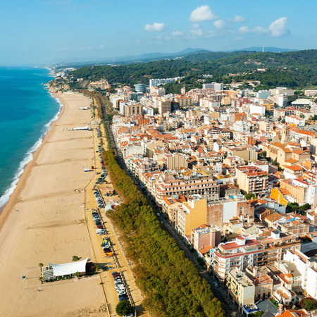 Aerial view of a densely built Spanish coastal town with a wide sandy beach running alongside the Mediterranean shoreline.