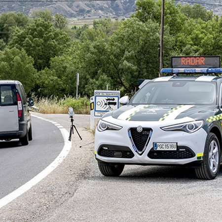 A Guardia Civil traffic patrol conducts a speed enforcement operation on a Spanish road using a mobile radar device.