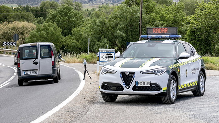 A Guardia Civil traffic patrol conducts a speed enforcement operation on a Spanish road using a mobile radar device.