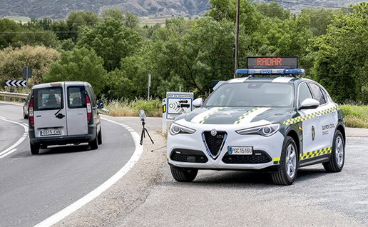 A Guardia Civil traffic patrol conducts a speed enforcement operation on a Spanish road using a mobile radar device.