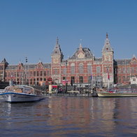 Tour boats pass Amsterdam Central Station along one of the city's famous canals in the Dutch capital.
