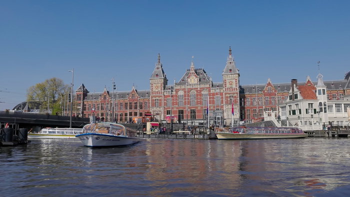 Tour boats pass Amsterdam Central Station along one of the city's famous canals in the Dutch capital.