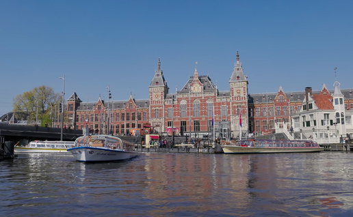 Tour boats pass Amsterdam Central Station along one of the city's famous canals in the Dutch capital.
