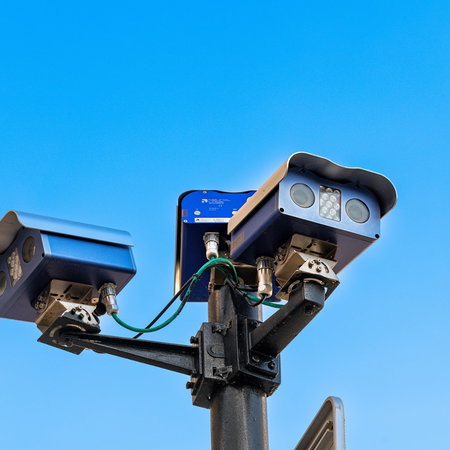 Automatic number plate recognition traffic cameras installed on a roadside monitoring passing vehicles.