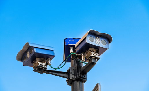 Automatic number plate recognition traffic cameras installed on a roadside monitoring passing vehicles.