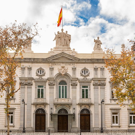 The Spanish Supreme Court building in Madrid, home to Spain's highest judicial authority, with the national flag flying above the main entrance.