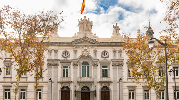 The Spanish Supreme Court building in Madrid, home to Spain's highest judicial authority, with the national flag flying above the main entrance.