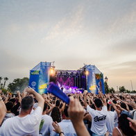 A large crowd at a festival in front of a stage